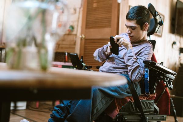 A young man who uses an electric wheelchair on his phone