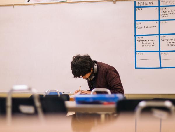 A teenager doing an exam alone in a classroom