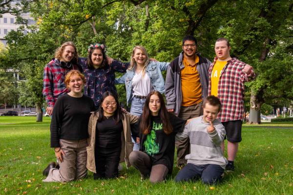 A group of Young Leaders graduates together in a park. They are smiling.
