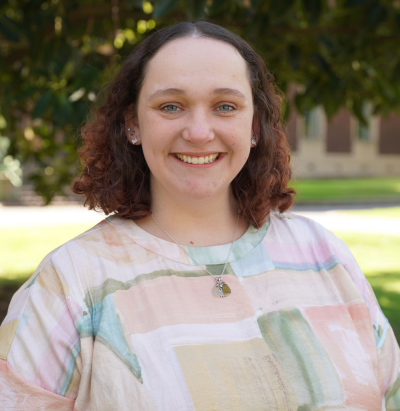 Casey, a person with curly brown hair smiling at the camera