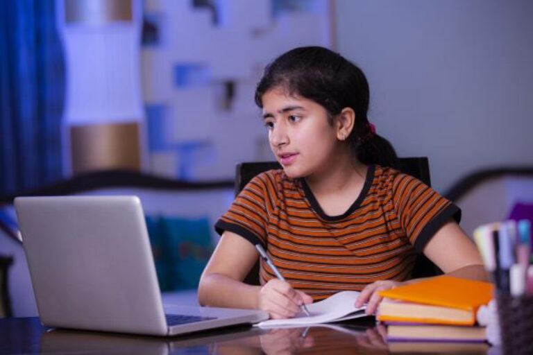 A girl with black hair sitting at a laptop