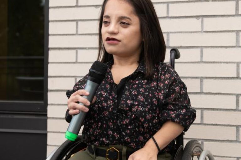 A young wheelchair user speaking into a microphone