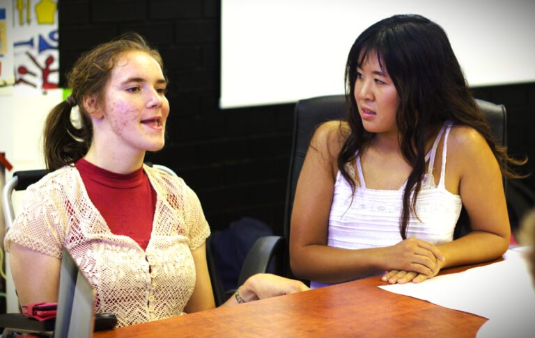 2 disabled young people chatting in a workshop setting